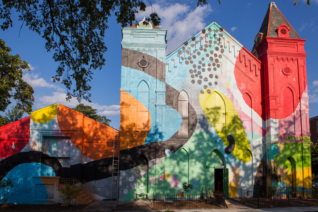 The exterior of Culture House DC, a former church painted in bright swirls and spots of colour.