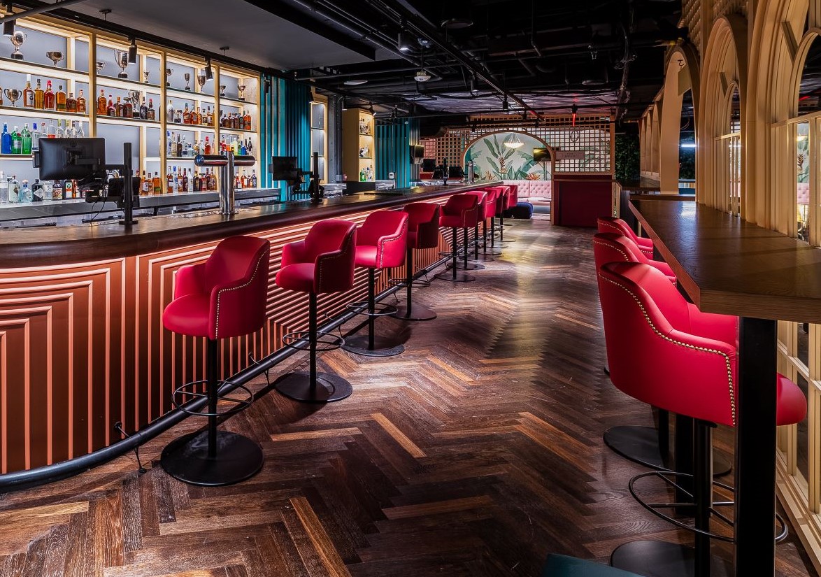 The Clubhouse Bar at Swingers Dupont Circle featuring red suede barstools, polished wooden surfaces and low lighting.