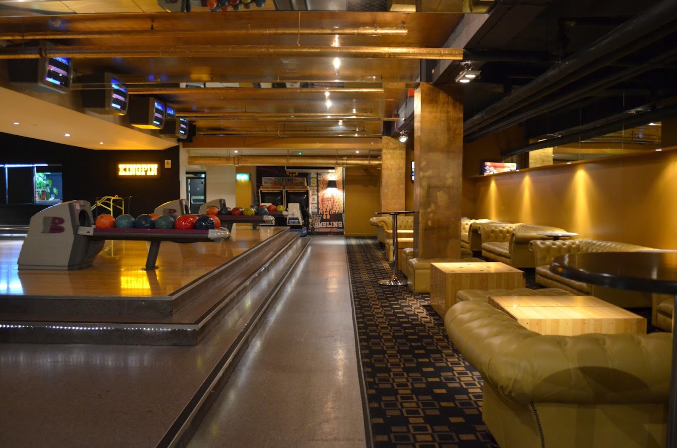 The yellow-and-black interior of the Kingpin Lounge, featuring yellow leather sofas and private bowling lanes.