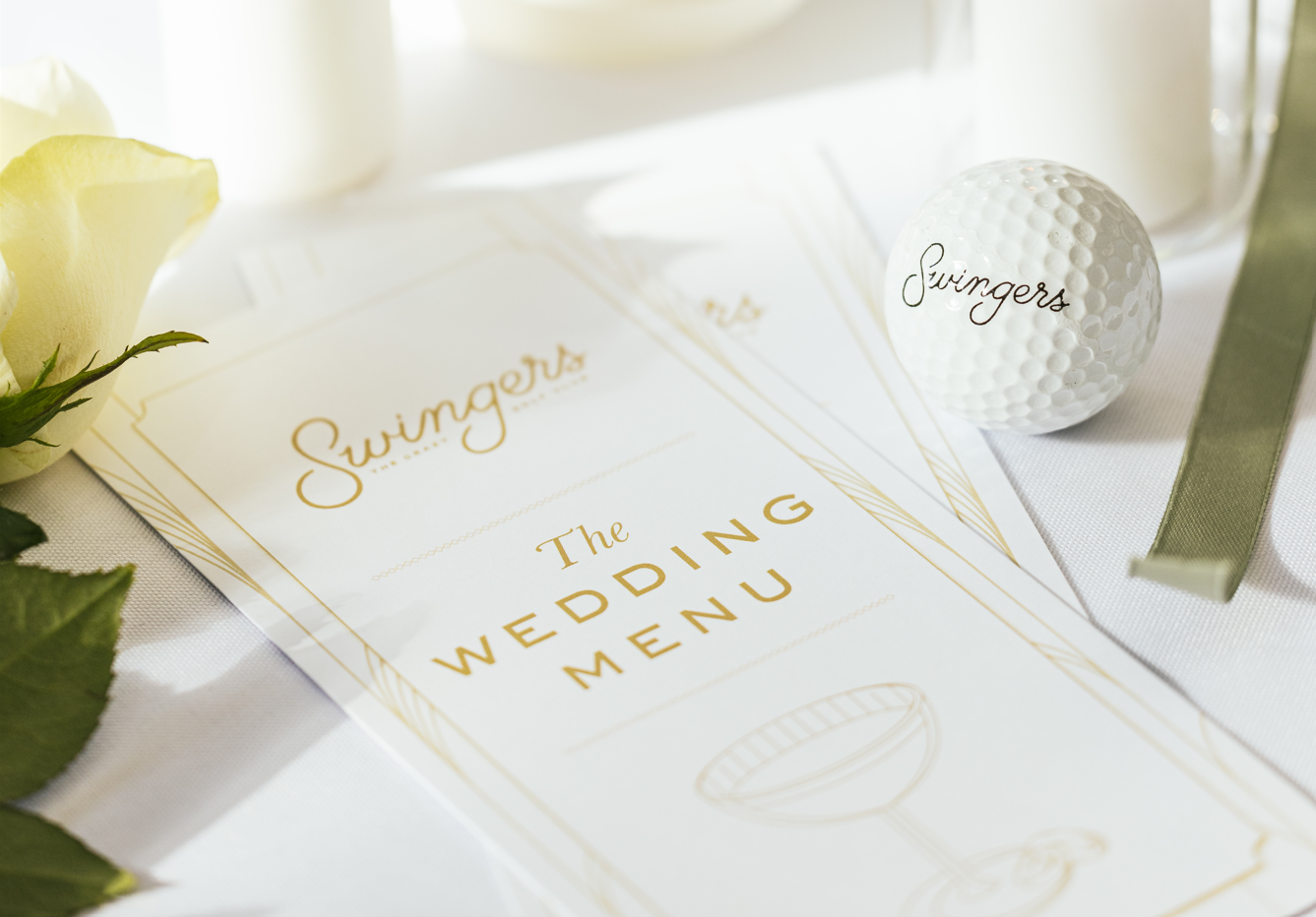 A Swingers wedding menu with white stationery and gold lettering.