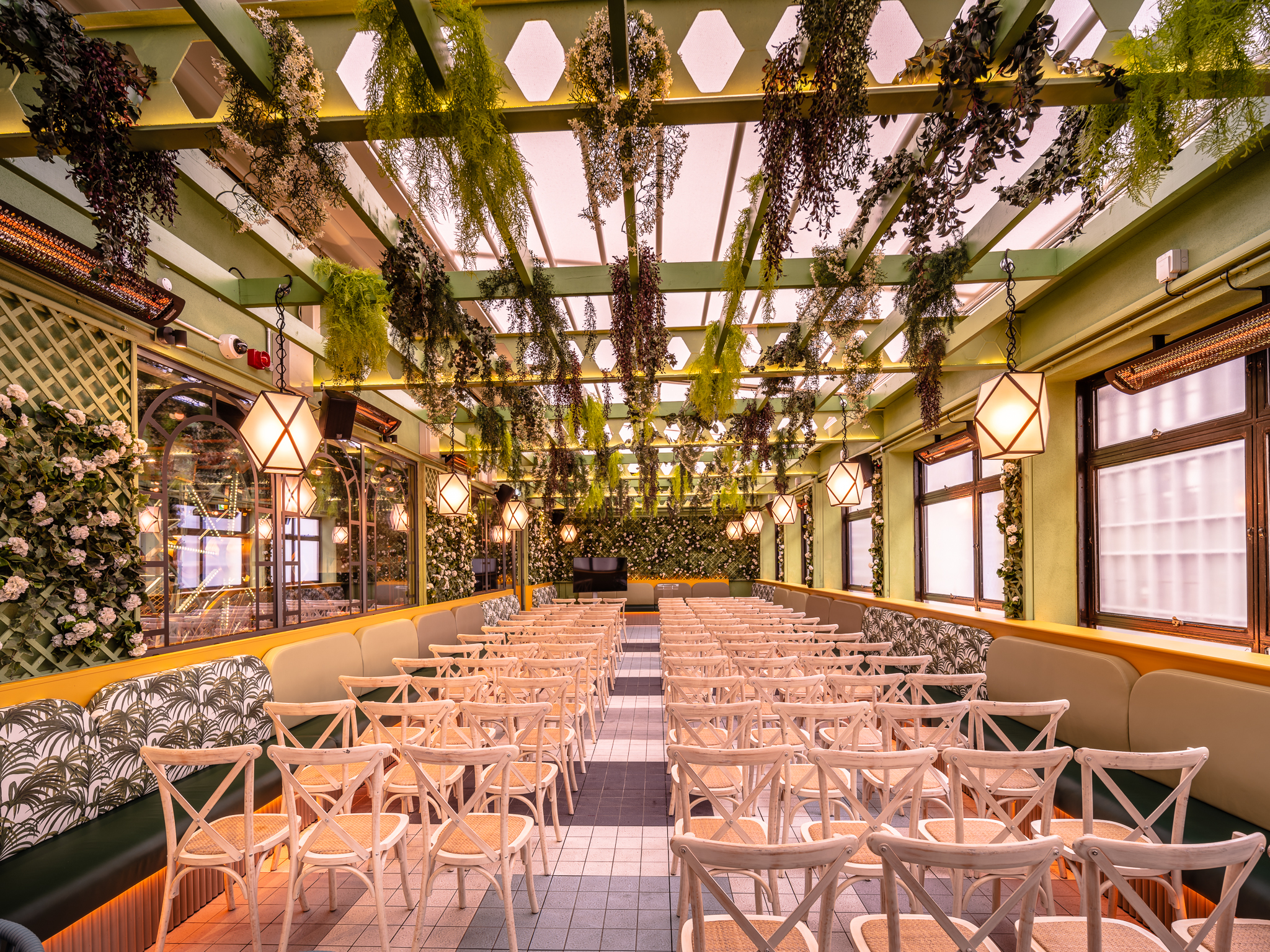 The Terrace room at Swingers West End, filled with rows of white chairs and botanical decorations.