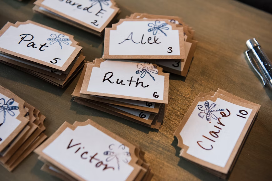 A table of hand-written name tags, each decorated with a dragonfly.