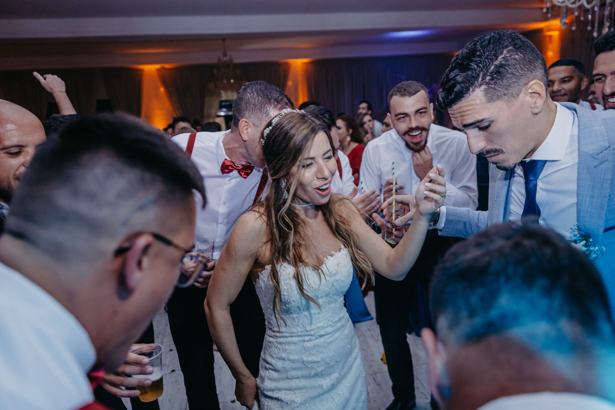 A group dances at a wedding with the bride and groom in the middle.