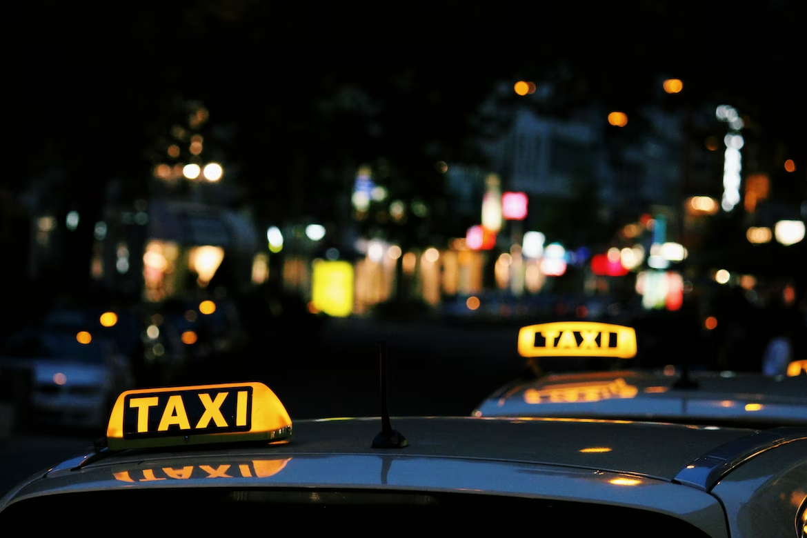 A line of cars with yellow “Taxi” signs lit up against the night.