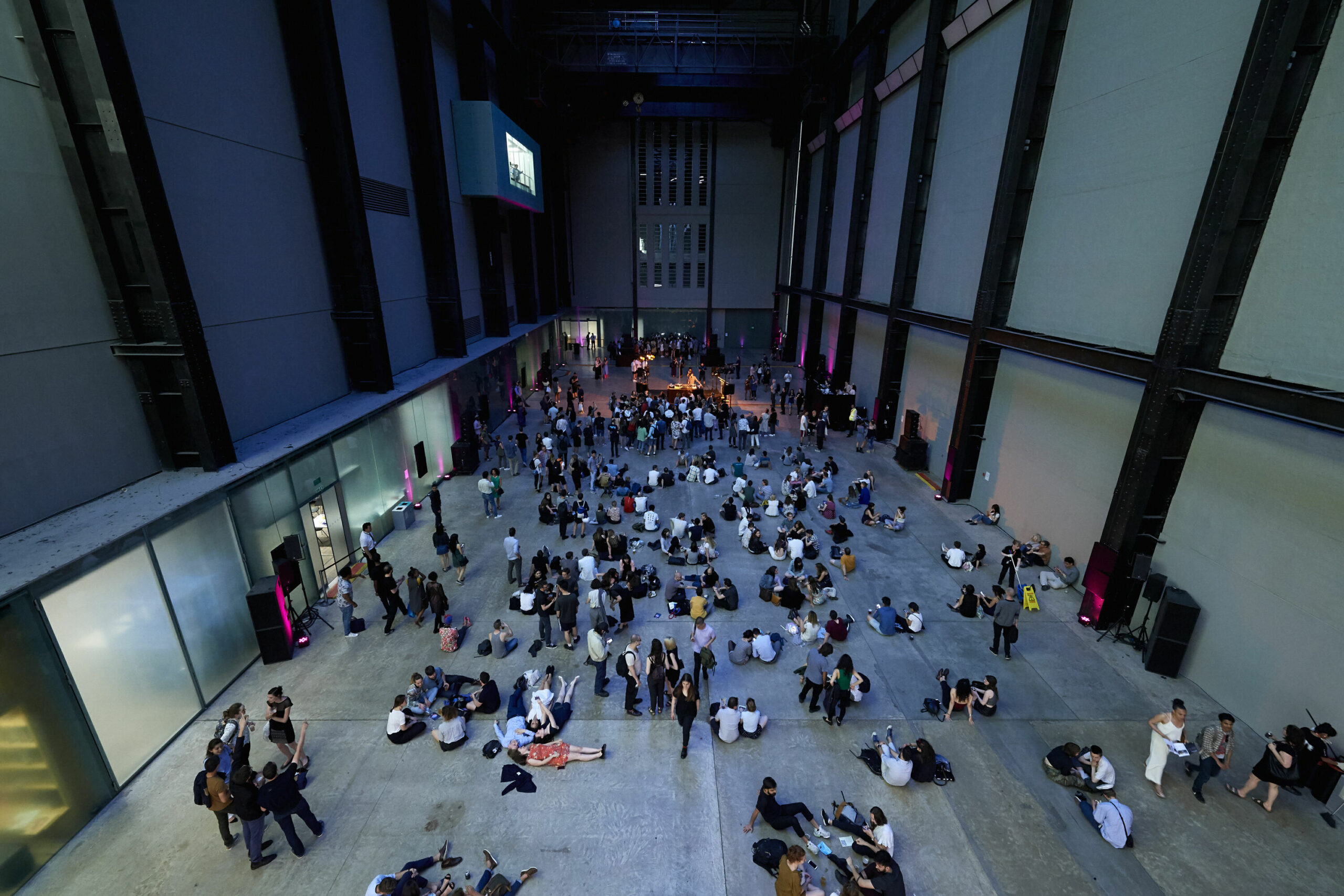 People move through the Tate Modern museum, looking small from this vantage point three stories above them.