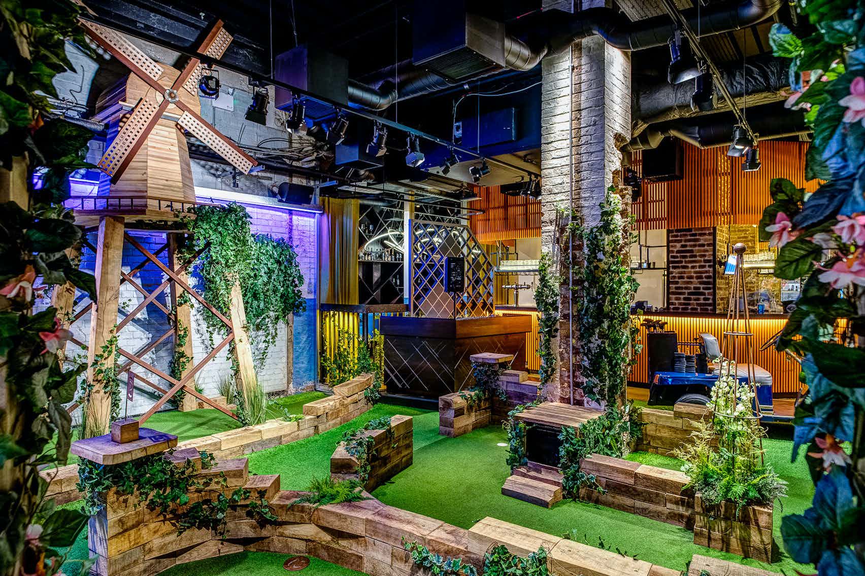 a mini golf course with a green faux grass floor and a windmill in an upscale venue