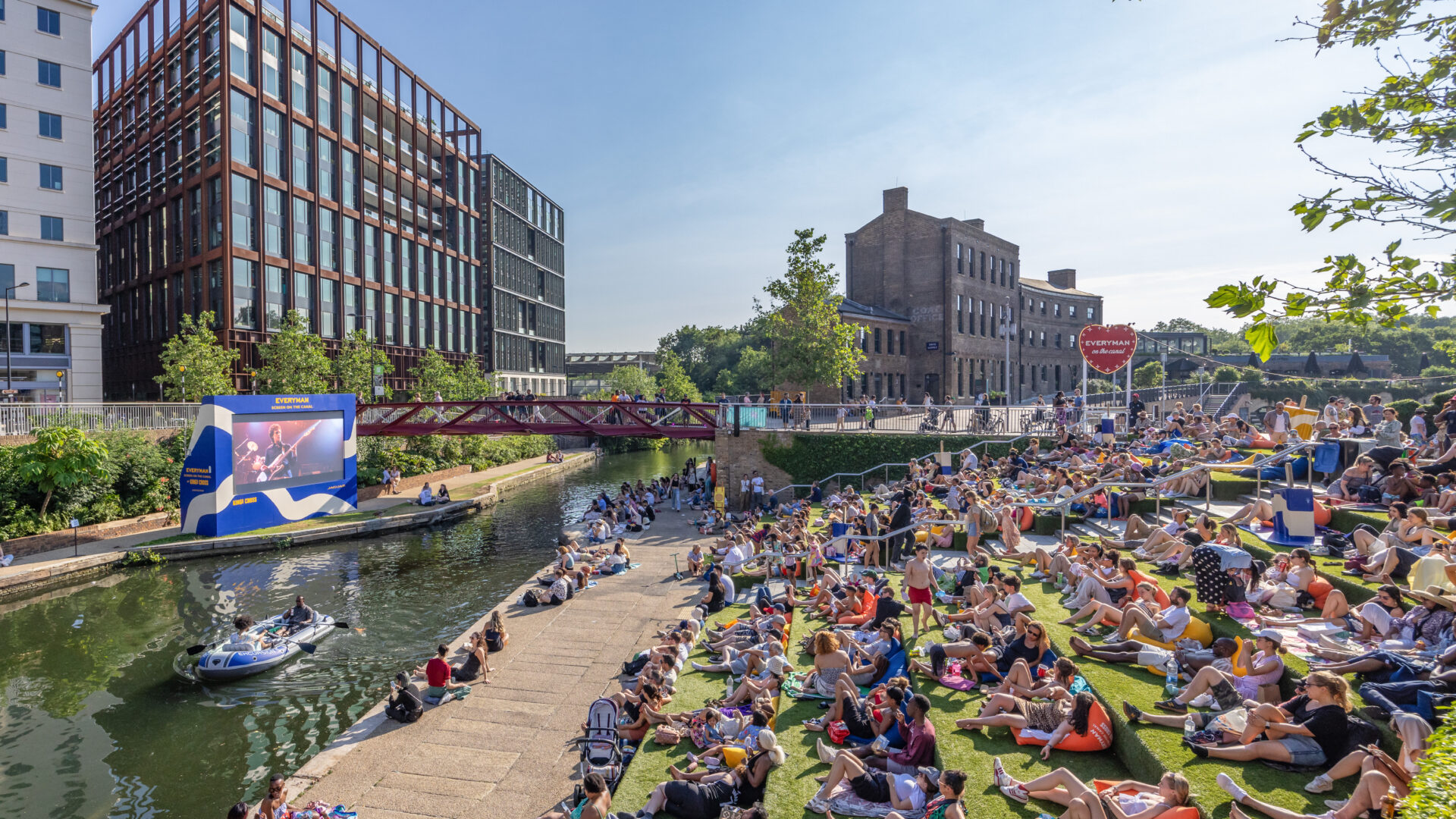 a picture of an open air cinema near kings cross on the river bank. many people are attending